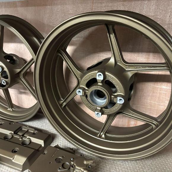 Powder coated motorcycle rims and metal parts in a warm bronze finish.